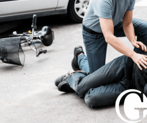 Close up of the legs of a pedestrian hit by a vehicle on their bike with someone helping them