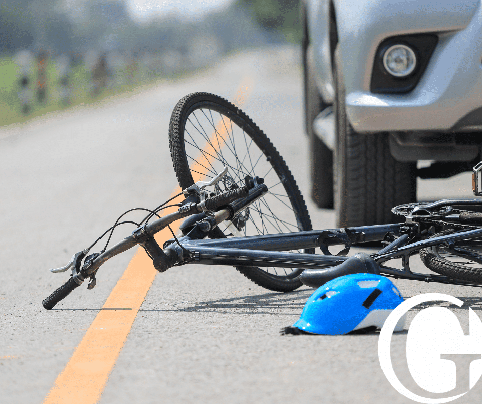 Lone bicycle flipped over on the road with a car in the background