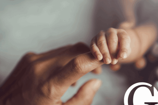 Closeup of a baby holding a mother's finger