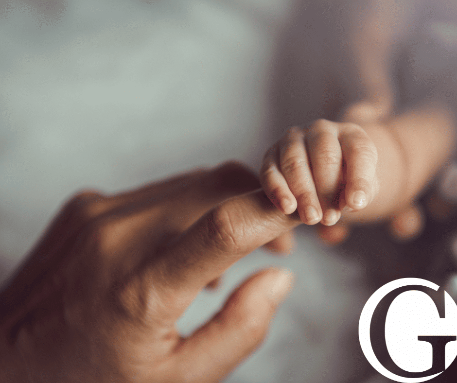 Closeup of a baby holding a mother's finger