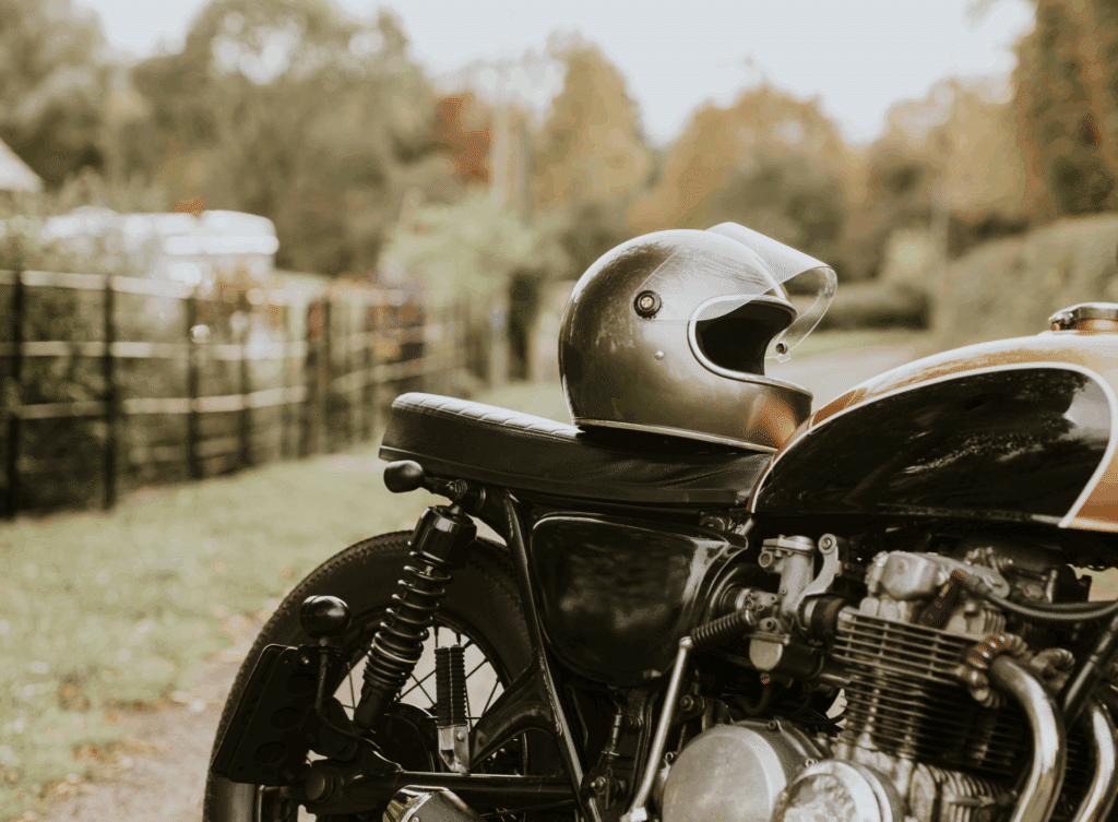 A helmet sitting on the seat of a motorcycle parked in the countryside