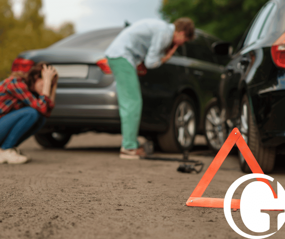 Two individuals with their head in their hands inspecting their vehicles after a collision
