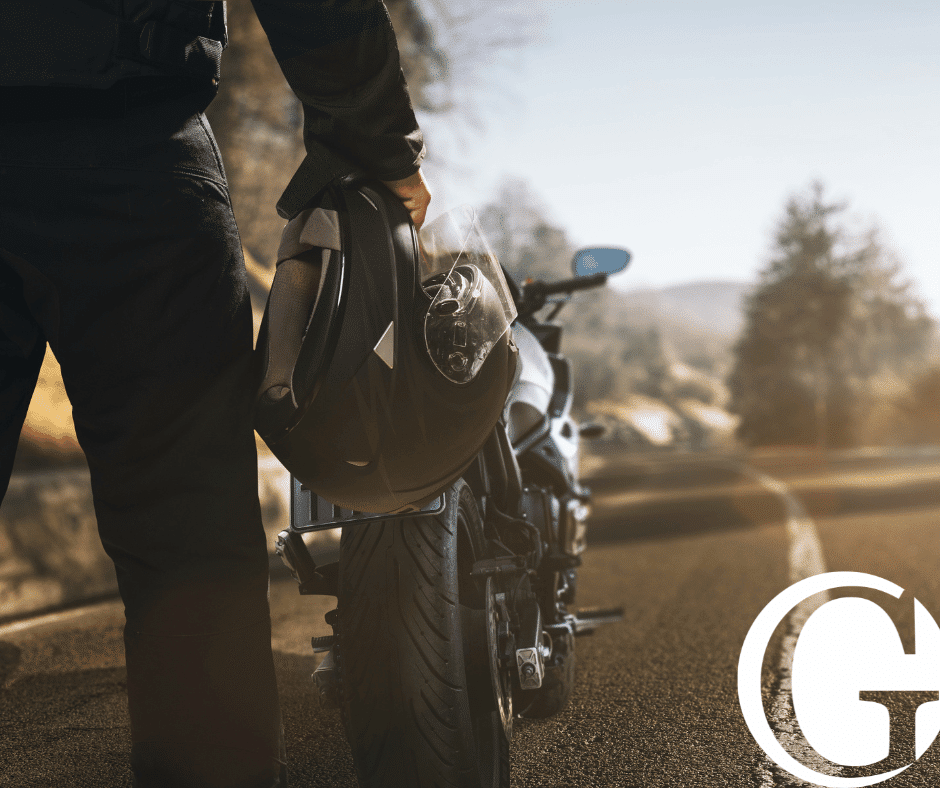 Closeup of motorcyclist holding a helmet while standing in front of a motorcycle